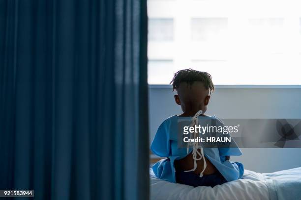 achteraanzicht van jongen zittend op bed in het ziekenhuis - child hospital bed stockfoto's en -beelden