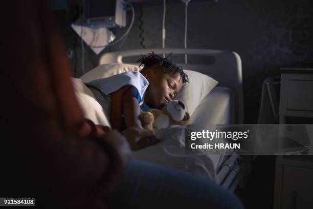 midsection mother sitting by sleeping boy on bed - children's hospital imagens e fotografias de stock