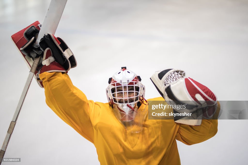 Successful ice hockey goaltender celebrating the victory with raised arms.