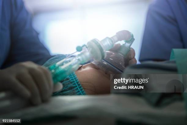 mädchen mit sauerstoffmaske von krankenschwestern im krankenhaus - bewusstlos stock-fotos und bilder