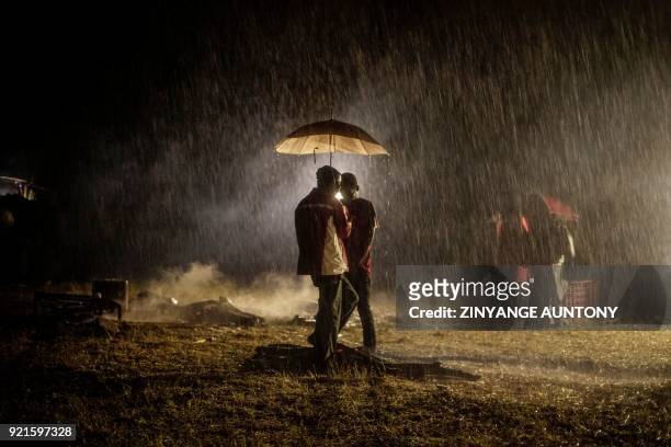 Supporters of the late opposition strongman Morgan Tsvangirai gather under an umbrella during a rains storm ahead of his burial in the village of...