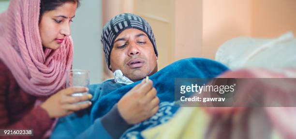 wife giving medicine to her ill husband. - sick wife stock pictures, royalty-free photos & images