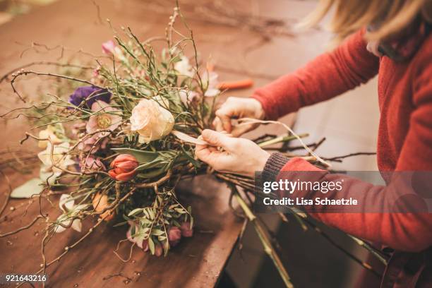 florist ties a bouquet of spring flowers - wearing flowers stock pictures, royalty-free photos & images