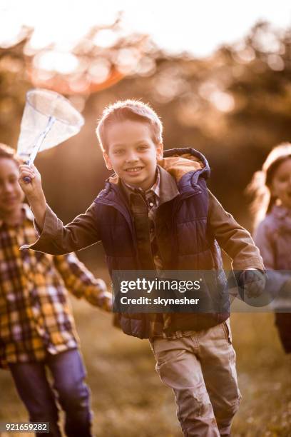 carefree boy chasing butterflies with his friends in spring day. - chasing butterflies stock pictures, royalty-free photos & images
