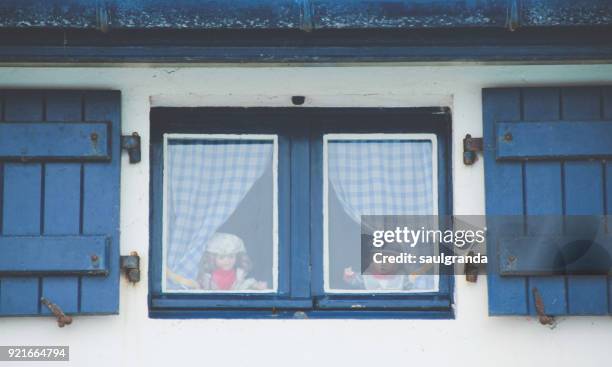 two dolls in a window - looking through a doll house stock-fotos und bilder