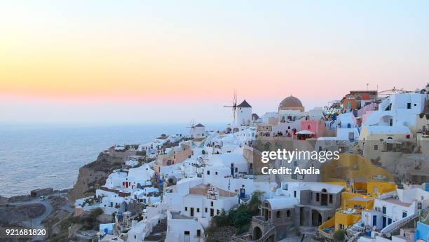 Greece, Cyclades, Santorini Island : sunset over the traditional whitewashed houses with colourful facades in the village of Oia.
