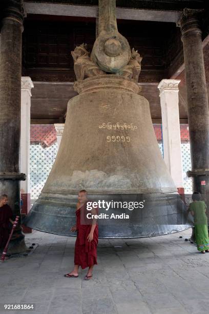 Buddhist monk in front of the Mingun Bell, one of the world's biggest bells.