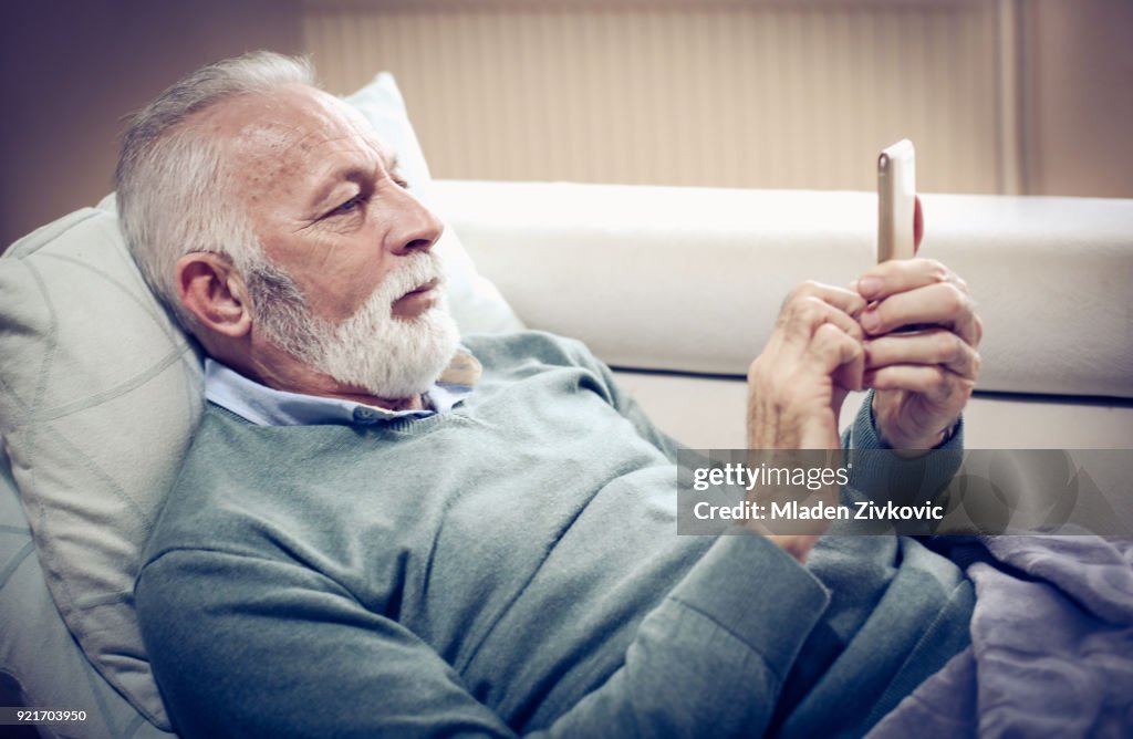 Äldre man med hjälp av smart telefon.