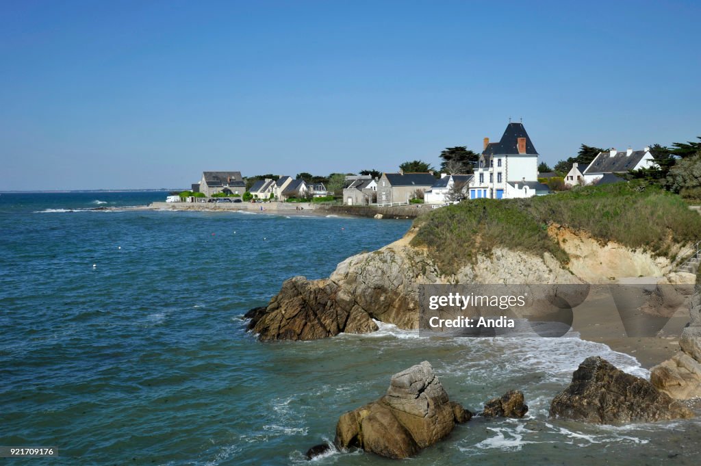 The rocky coast in the foreground and houses along the waterfront in the background viewed from the 'pointe du Castelli' headland.