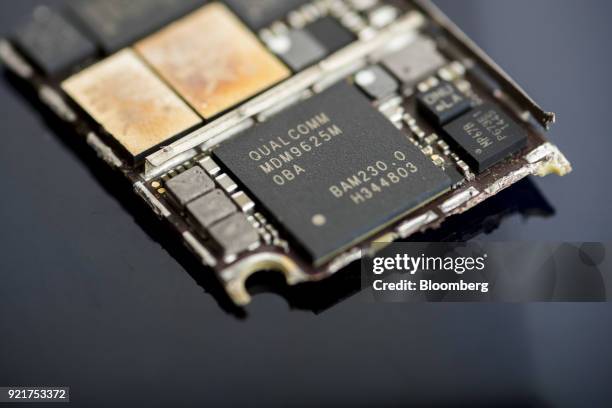 Qualcomm Inc. Baseband modem integrated circuit chip, center, of an Apple Inc. IPhone 6 smartphone is seen in an arranged photograph in Bangkok,...