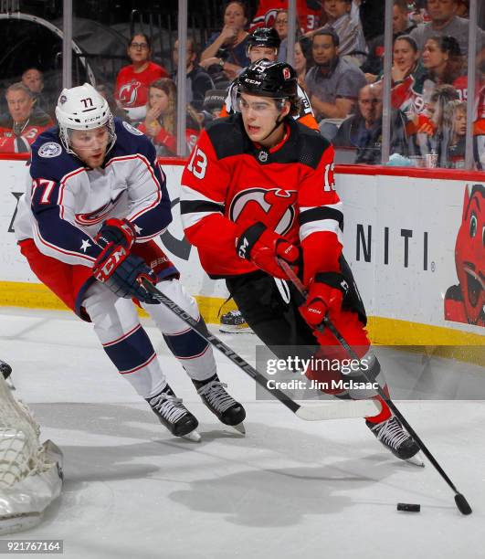 Nico Hischier of the New Jersey Devils skates with the puck against Josh Anderson of the Columbus Blue Jackets during the first period on February...