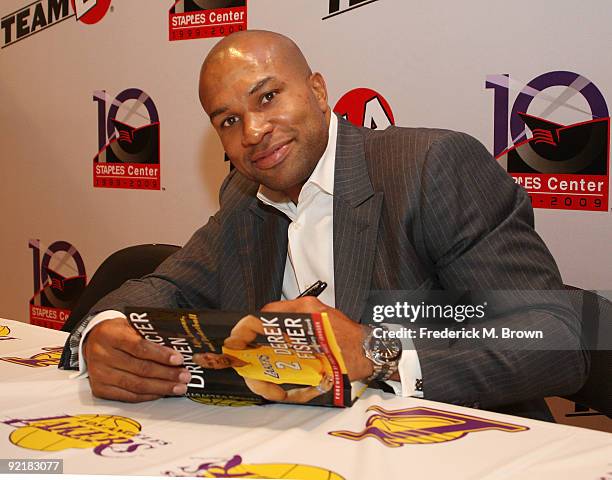 Los Angeles Lakers basketball player Derek Fisher signs a copy of his new book "Character Driven" during the press conference celebrating the 10th...