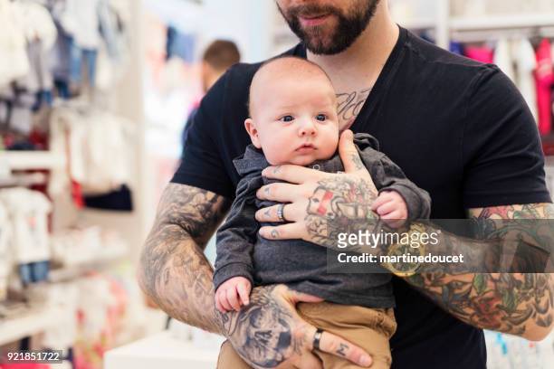 father shopping with young baby in a children store. - baby boutique stock pictures, royalty-free photos & images