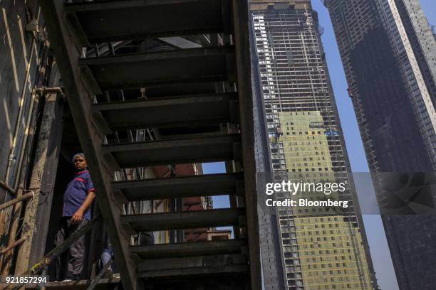 Man stands on an exterior stairwell as the two towers of Trump Tower Mumbai stand under construction at Lodha The Park, a luxury residential project...