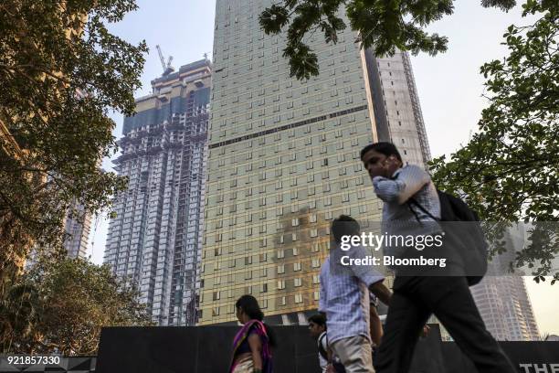 Pedestrians walk past as one of two towers of Trump Tower Mumbai, center, stands under construction at Lodha The Park, a luxury residential project...