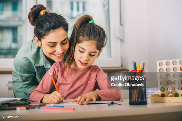 mother helping her daughter while studying - children stock pictures, royalty-free photos & images