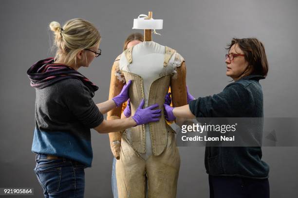 Members of the conservation team wear protective gloves during the fitting of a 'pair of straight bodies' to the funeral effigy of Elizabeth I at...