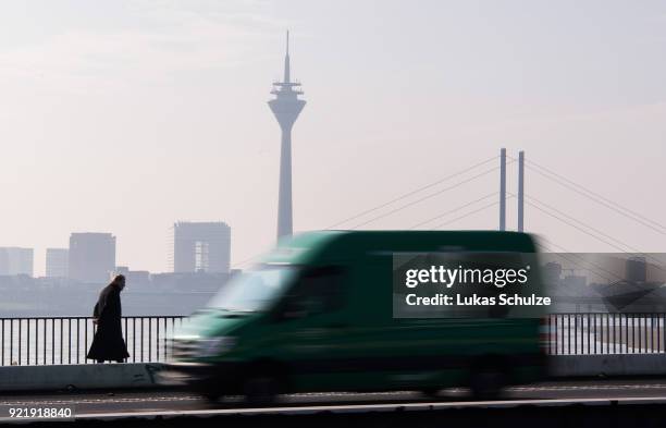 Van drives along the Rhine River as the Rheinturm telecommunications towers stands behind on February 20, 2018 in Dusseldorf, Germany. The German...