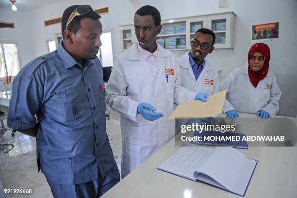 Photo taken on January 24 shows a police officer from criminal investigation department speaking with Labratory technicians as he brings samples to...