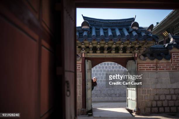 Tourist pokes her head around a doorway as she visits Gyeongbokgung Palace on February 21, 2018 in Seoul, South Korea. With tourists visiting from...