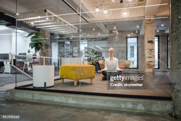 young relaxed female entrepreneur exercising yoga in the office. - office zen stock pictures, royalty-free photos & images