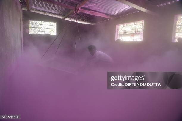 An Indian labourer sifts coloured powder to be used during the forthcoming spring festival of Holi, at a factory in Fulbari village, on the outskirts...