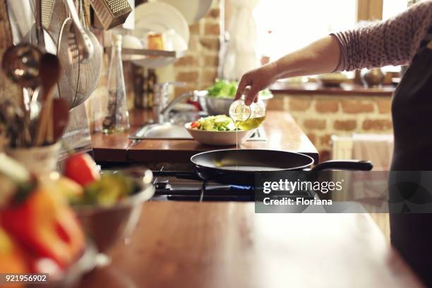 cooking vegetables, step four, pouring the olive oil - kitchen skillet stock pictures, royalty-free photos & images
