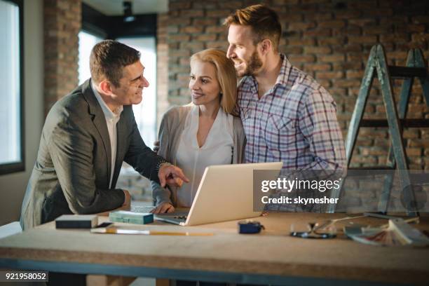 happy bouw aannemer en jonge paar communiceren tijdens het gebruik van de computer op de bouwplaats. - architect stockfoto's en -beelden