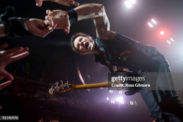 Green Day bass player Mike Dirnt reaches out to touch audience hands while performing on stage at SECC on October 19, 2009 in Glasgow, Scotland.