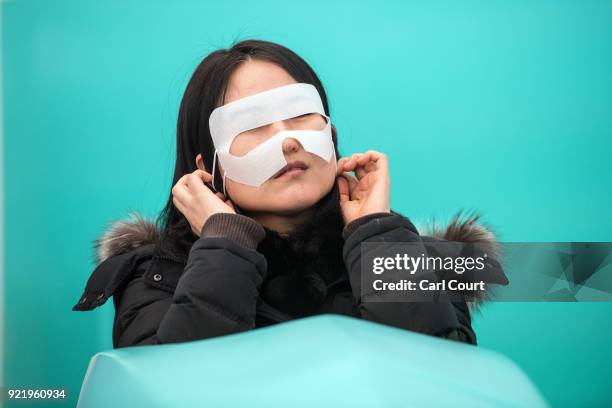 Woman puts on a hygienic face-mask before wearing a virtual reality headset as she tries a virtual bobsleigh in the PyeongChang 2018 Winter Olympics...