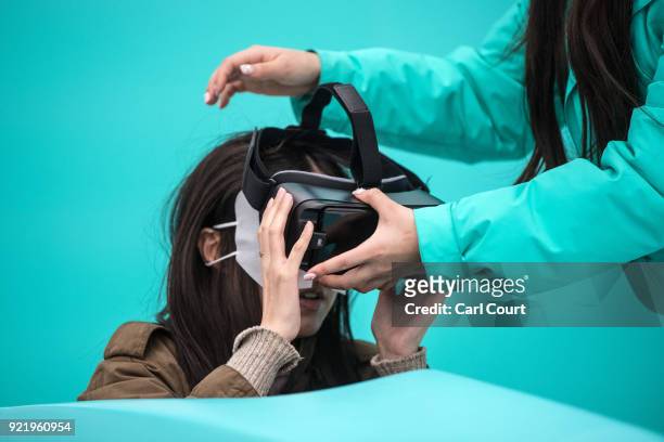 An assistant helps a visitor with a virtual reality headset as she tries a virtual bobsleigh in the PyeongChang 2018 Winter Olympics Live Site on...
