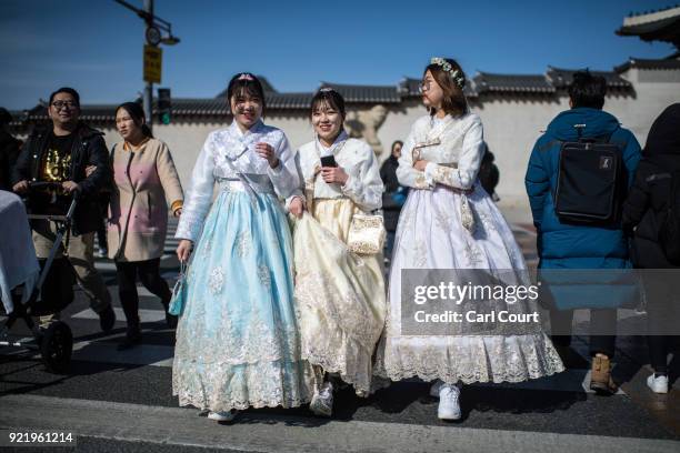 Women wearing traditional Korean Hanbok dresses cross a road near Gyeongbokgung Palace on February 21, 2018 in Seoul, South Korea. With tourists...