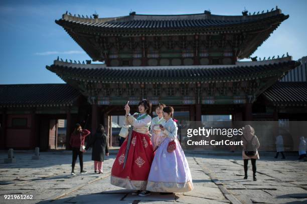Women wearing traditional Korean Hanbok dresses take a selfie photograph as they visit Gyeongbokgung Palace on February 21, 2018 in Seoul, South...