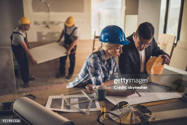 female foreman and male architect analyzing blueprints at construction site. - rebuilding stock pictures, royalty-free photos & images