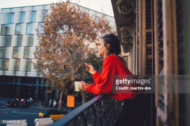entspannte frau rauchen auf der terrasse - woman smoking cigarette stock-fotos und bilder
