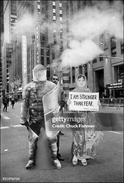 View of a pair of cardboard figures, held by mostly obscured demonstrators, on Sixth Avenue during the Women's March on New York, New York, New York,...