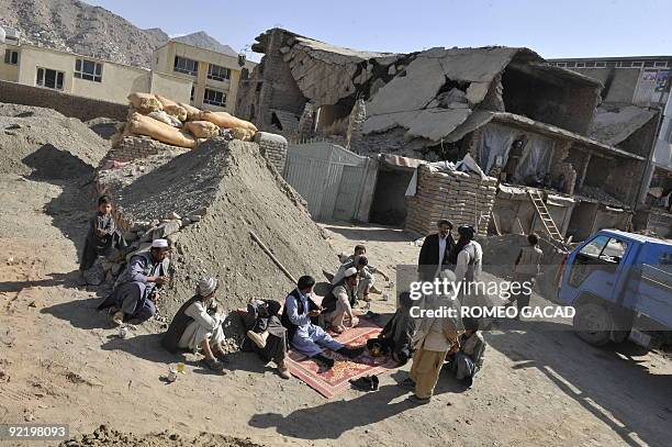 Workers rest near the ruins of a building in Kabul on October 22 destroyed during the Afghanistan's bloody civil war from 1992-1996 that turned the...