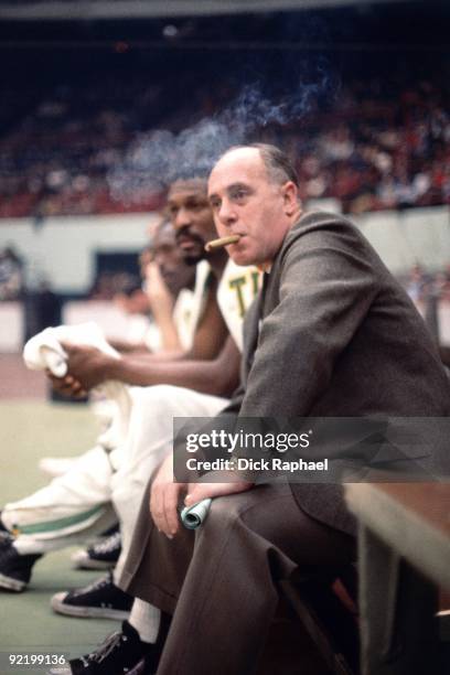 Red Auerbach, haed coach of the Boston Celticcs smokes a cigar on the bench during a game played in 1965 at the Boston Garden in Boston,...