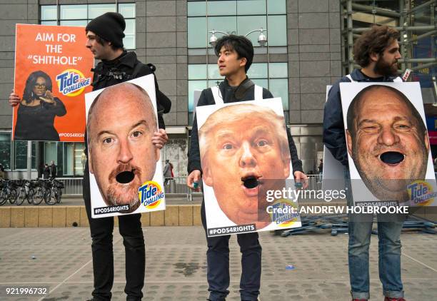 People hold up images of accused sexual predators, Harvey Weinstein, Woody Allen, President Trump, Louis CK and "Tide Challenge" during the Women's...