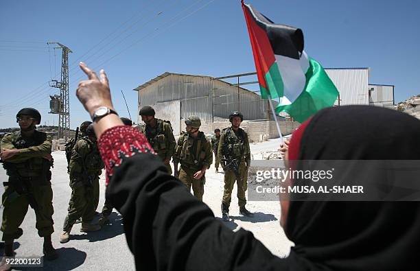 Palestinian woman flashes the victory sign in front of Israeli soldiers during a demonstration against Israel's separation barrier in the West Bank...