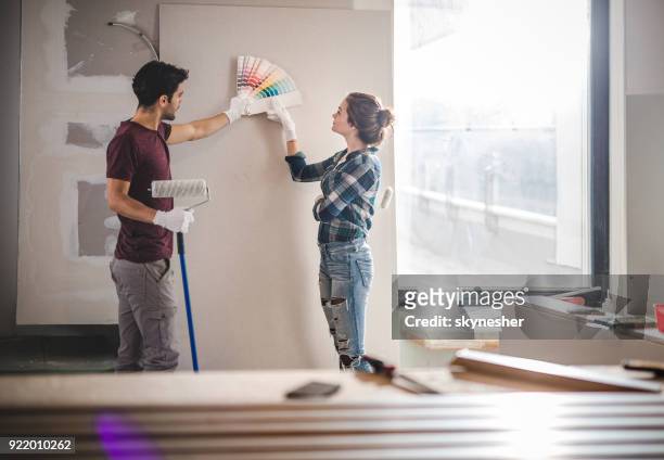 giovane coppia che sceglie il colore giusto per la propria parete durante la ristrutturazione dell'appartamento. - vita domestica foto e immagini stock