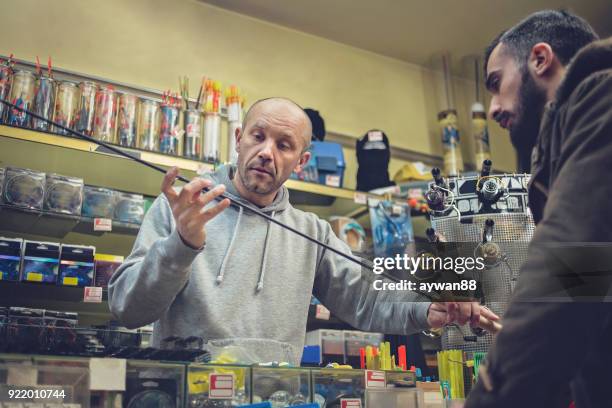 young man buying fishing rod - barbed hook stock pictures, royalty-free photos & images