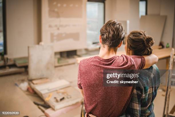 achteraanzicht van omarmd paar in hun renoveren appartement. - home addition stockfoto's en -beelden