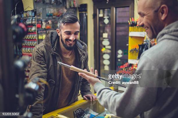 man buying fishing rod in a store - barbed hook stock pictures, royalty-free photos & images