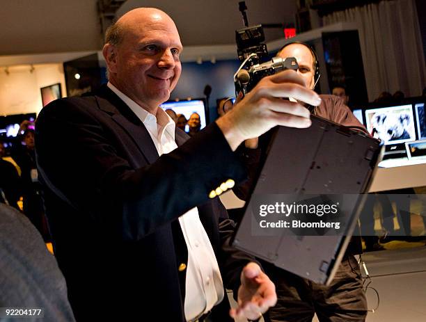 Steve Ballmer, chief executive officer of Microsoft Corp., holds a Sony VIAO laptop between two fingers as he looks over PCs running Windows 7 during...