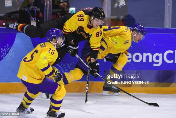 Germany's David Wolf and Sweden's Staffan Kronwall fight for the puck as Sweden's Simon Bertilsson looks on in the men's quarter-final ice hockey...