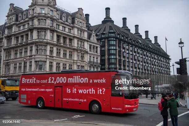 Bus with the campaign motto: "Brexit to cost £2,000 million a week says government's own report. Is it worth it?" passes a crossing near the Houses...