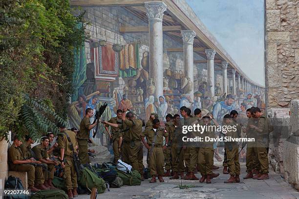 Israeli soldiers are seen against a mural depicting the continuation of the Cardo, the ancient Roman central shopping street that ran through the...