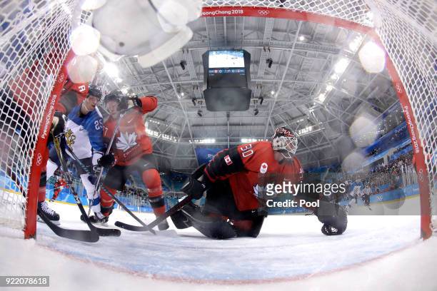 Jonas Enlund of Finland and Cody Goloubef of Canada compete for the puck as Ben Scrivens makes a save in the first period during the Men's Play-offs...