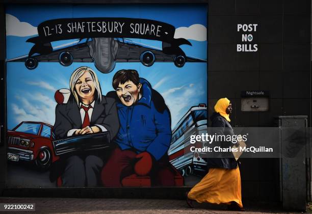 Woman walks past a mural depicting Sinn Fein vice president Michelle O'Neill and DUP leader Arlene Foster as the unlikely bedfellow characters from...